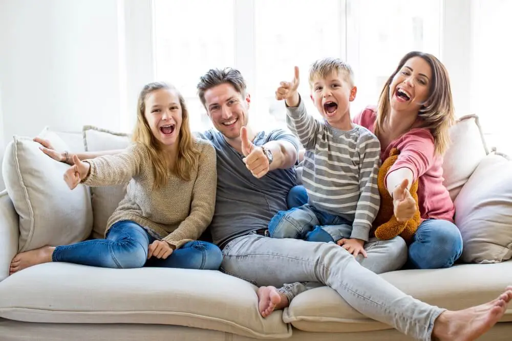 Junge Familie sitzt auf der Couch und freut sich auf Ihren Sozialumzug